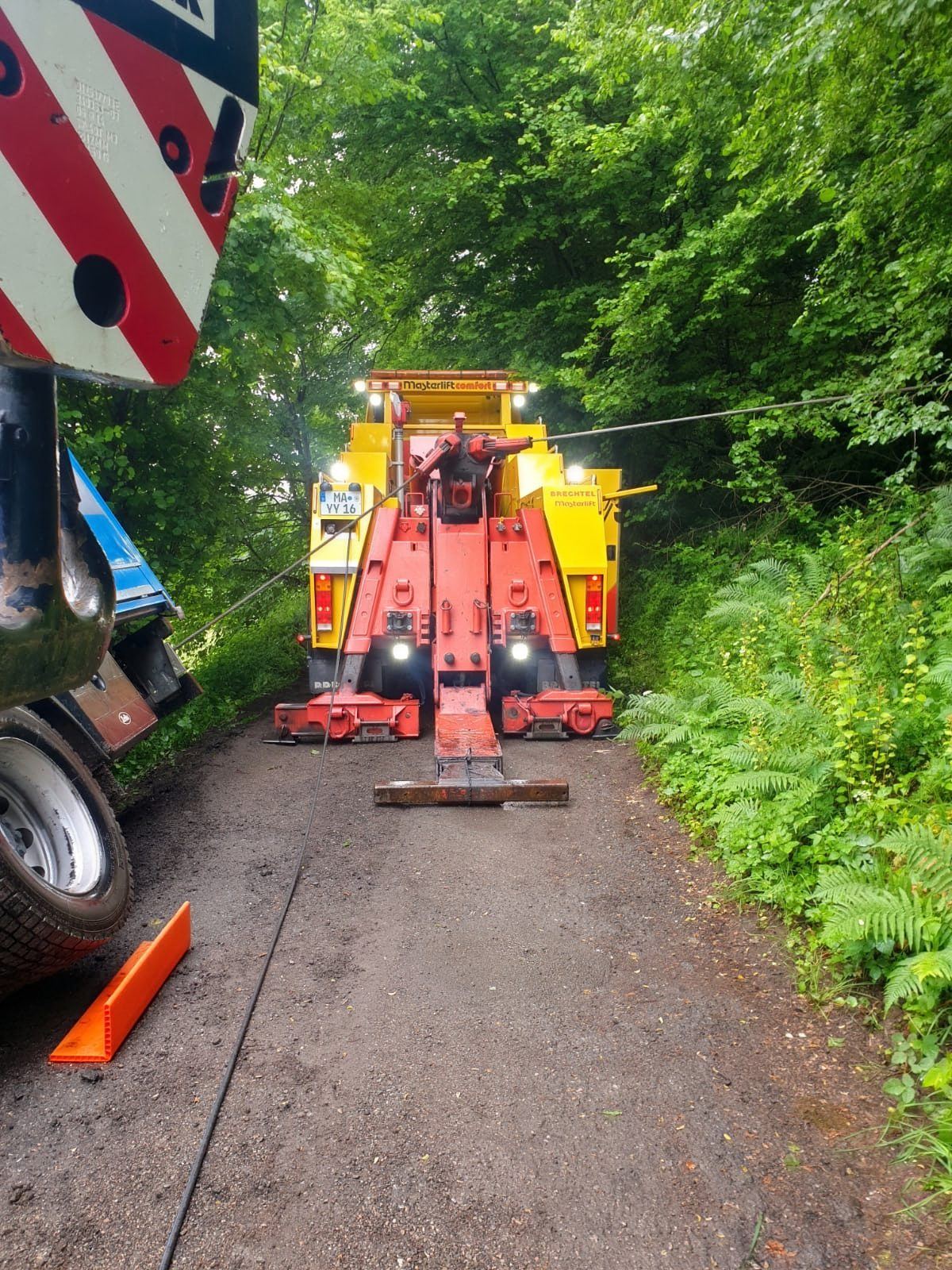Roter Bergewagen der STALF KG mit ausgelegter Seilwinde auf einem Waldweg