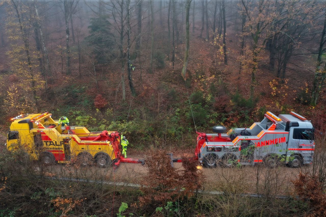 Luftaufnahme: gelbes und rotes Bergefahrzeug der STALF KG auf einer Waldstraße bei einem Einsatz