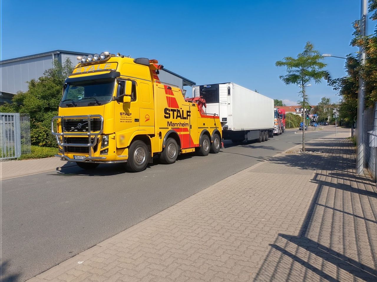 Gelbes Bergefahrzeug der STALF KG überführt einen Sattelzug auf einer Straße in Mannheim